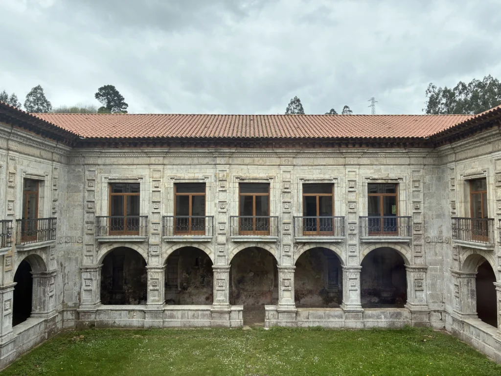 Claustro barroco del Monasterio de San Salvador de Cornellana en Salas, Asturias, con sus arcos de piedra y balcones tradicionales.