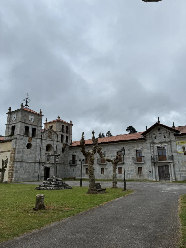 Plaza exterior del Monasterio de San Salvador de Cornellana con el crucero de piedra, la iglesia románica y el palacio barroco en Asturias.