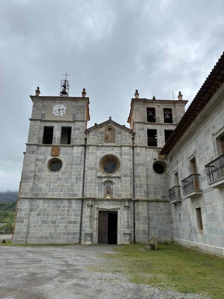 Fachada de la iglesia de San Salvador de Cornellana con sus torres campanario, rosetón central y reloj, joya del románico y barroco en Asturias.