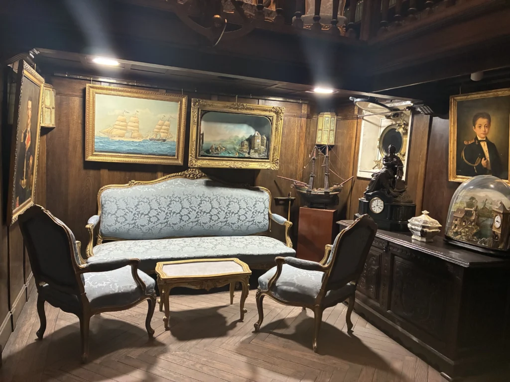 Recreación de un salón de época en el Museo Naval de Madrid con mobiliario clásico, pinturas navales, maquetas de barcos y objetos decorativos marineros.