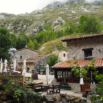 Arquitectura tradicional de piedra en Bulnes de Abajo con bares y terrazas bajo las montañas de Picos de Europa.