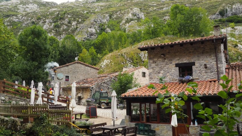 Arquitectura tradicional de piedra en Bulnes de Abajo con bares y terrazas bajo las montañas de Picos de Europa.