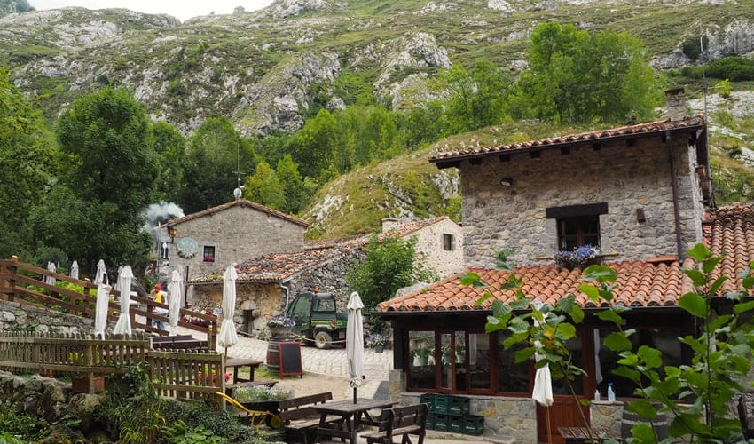 Arquitectura tradicional de piedra en Bulnes de Abajo con bares y terrazas bajo las montañas de Picos de Europa.