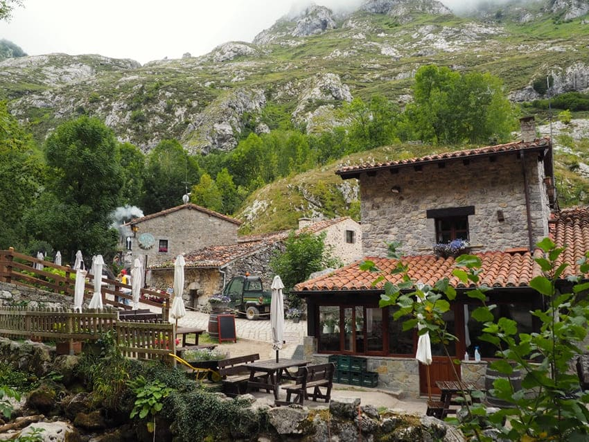 Arquitectura tradicional de piedra en Bulnes de Abajo con bares y terrazas bajo las montañas de Picos de Europa.