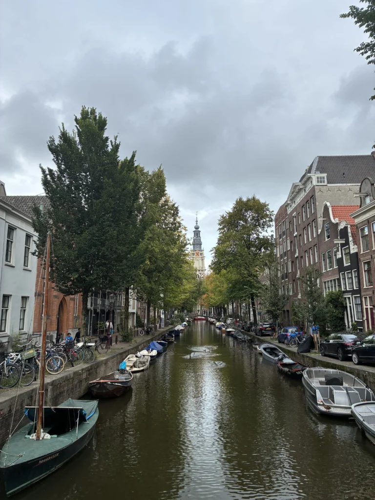 Perspectiva del canal Groenburgwal con árboles de otoño y la torre de la iglesia Zuiderkerk al fondo.
