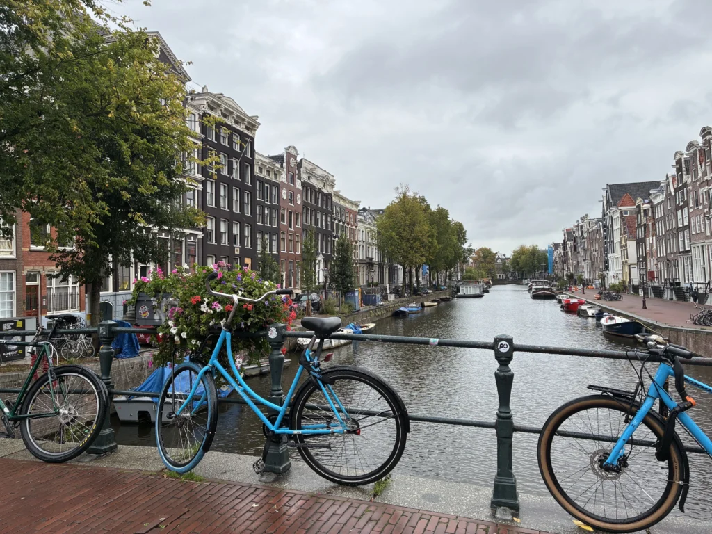 Bicicletas de color azul turquesa atadas a la barandilla de un puente sobre el canal Keizersgracht en otoño.