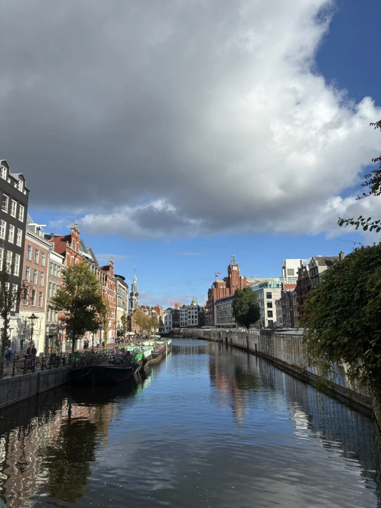 Vista del canal Singel en Ámsterdam con los puestos flotantes del Mercado de las Flores y la torre Munttoren al fondo.